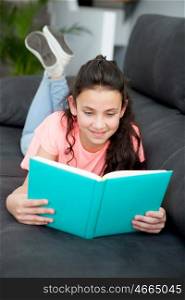 Young girl reading a book on the sofa at home