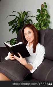 Young girl reading a book on the sofa at home