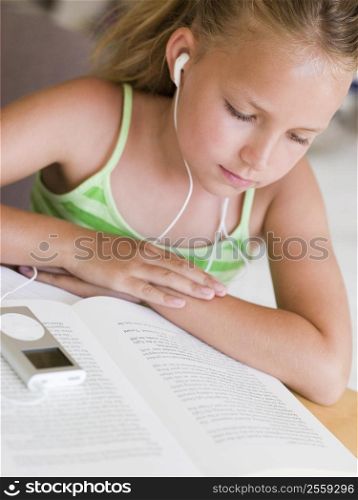 Young Girl Reading A Book While Listening To An MP3 Player