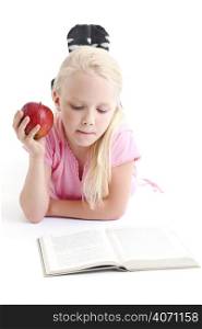 Young girl reading and eating an apple