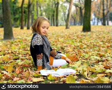 young girl reads a book in the autumn park. young girl reads a book in the autumn park young girl reads a book in the autumn park lying on the ground