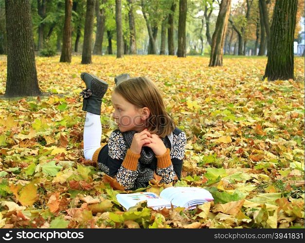 young girl reads a book in the autumn park. young girl reads a book in the autumn park lying on the ground