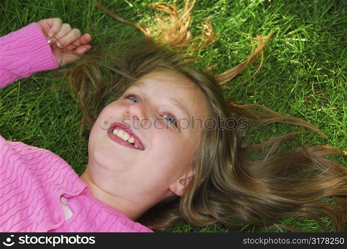 Young girl relaxing on green grass outside