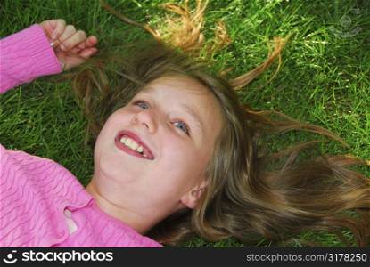 Young girl relaxing on green grass outside