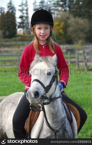 Young girl riding a white pony at countryside