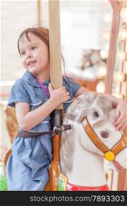 Young girl riding carousel horse at amusement park
