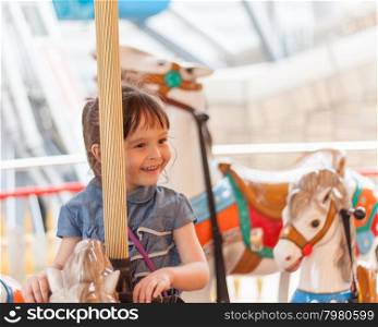 Young girl riding carousel horse at amusement park