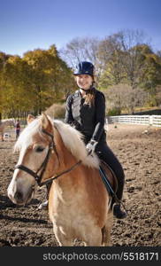 Young girl riding horse. Portrait of teenage girl riding horse outdoors on sunny autumn day