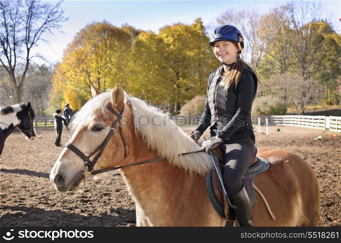Young girl riding horse. Portrait of teenage girl riding horse outdoors on sunny autumn day