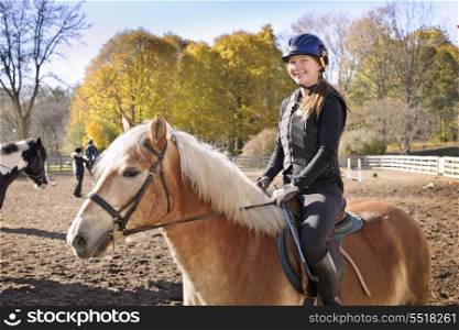 Young girl riding horse. Portrait of teenage girl riding horse outdoors on sunny autumn day