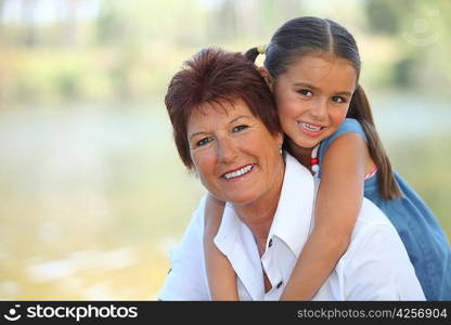 Young girl riding piggy-back on her grandmother&acute;s back