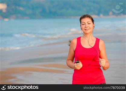 young girl running and listening to music on the beach