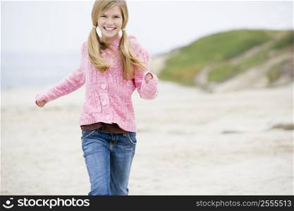 Young girl running at beach smiling