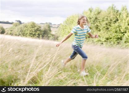 Young girl running in a field smiling