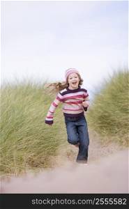 Young girl running on beach smiling