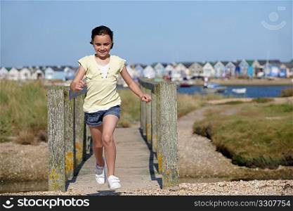 young girl running towards camera with beach huts in backgrounds