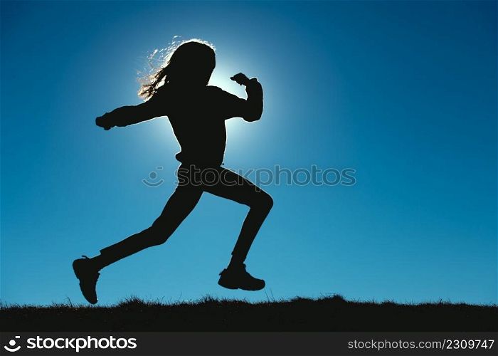 Young girl runs in the meadows in silhouettes with the sun behind her face