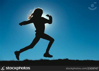 Young girl runs in the meadows in silhouettes with the sun behind her face