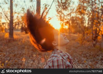 Young girl shaking her head in sunset light while in the woodland