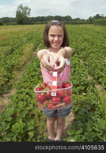 Young girl showing a container of strawberries she has picked