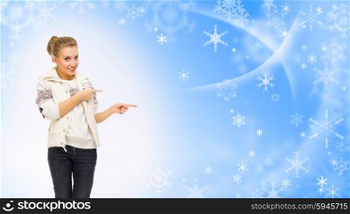Young girl shows pointing gesture on blue winter background