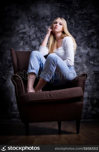 Young girl sit on the chair on grey wall background