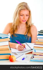 Young girl sitting at table with lots of books and doing homework&#xA;