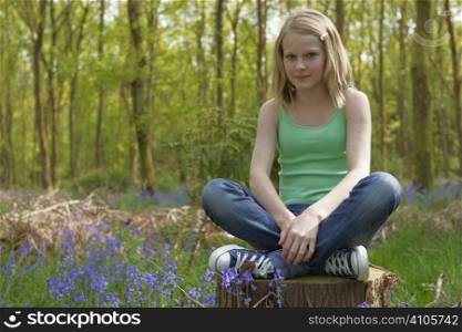 young girl sitting in a forest enjoying the fresh air