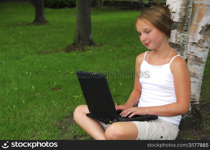 Young girl sitting in a park with laptop computer