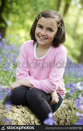 young girl sitting in a wood full of bluebells