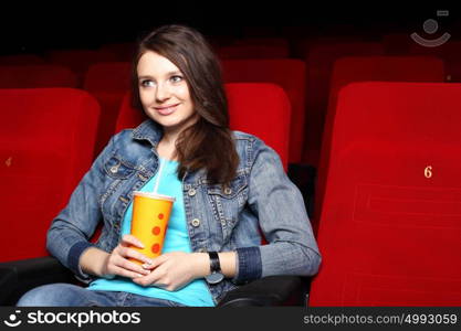 Young girl sitting in cinema and watching movie