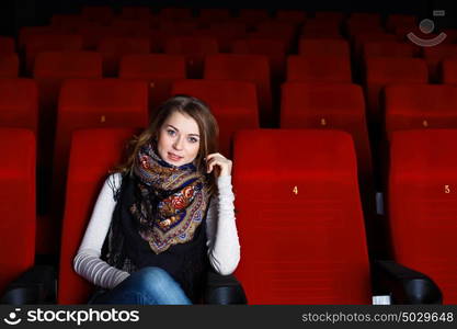 Young girl sitting in cinema and watching movie