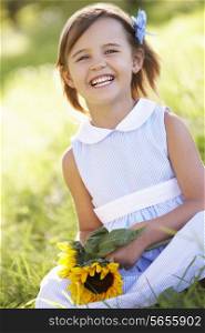 Young Girl Sitting In Summer Field Holding Sunflower