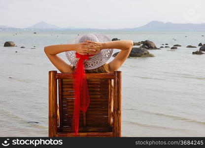 young girl sitting on a chair and looks at the sea