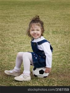 Young girl sitting on a football