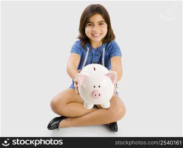 Young girl sitting on floor and holding and showing a piggybank