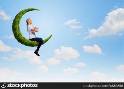 Young girl sitting on green moon high in sky. Woman on moon