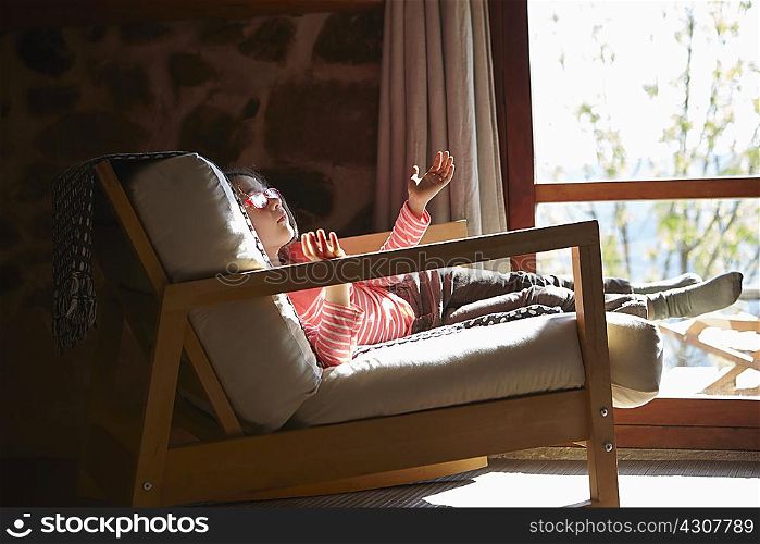 Young girl sitting on rocking chair daydreaming