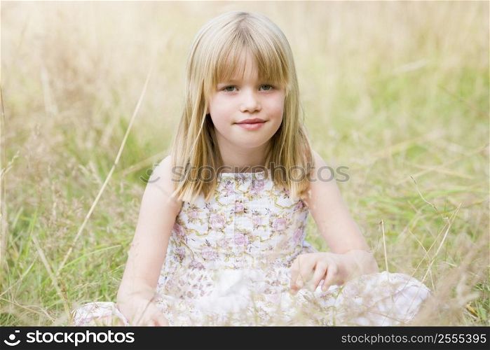 Young girl sitting outdoors smiling
