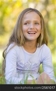 Young girl sitting outdoors smiling