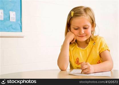 Young Girl Smiling in Classroom Writing on Paper