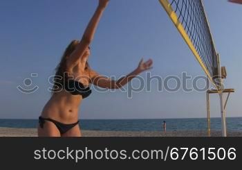 Young girl spends summer vacation on the beach playing volleyball with friends
