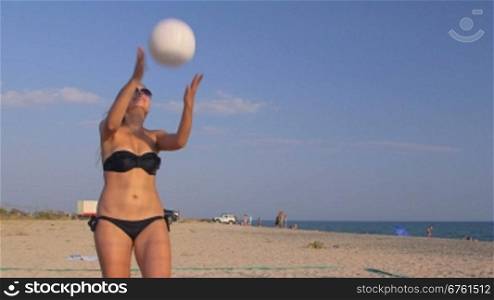 Young girl spends summer vacation on the beach playing volleyball with friends