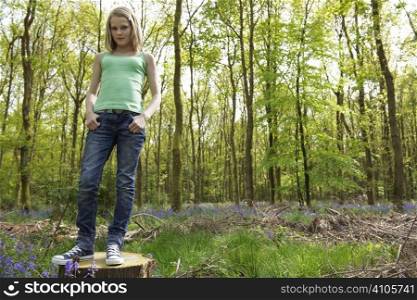 young girl standing in a forest enjoying the fresh air