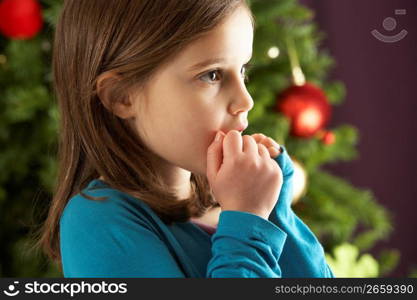 Young Girl Standing In Front Of Christmas Tree