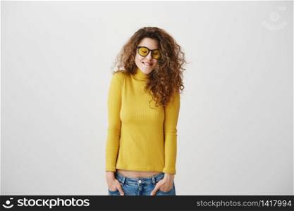 Young girl standing isolated on grey wall playing around looking camera smiling happy close-up.. Young girl standing isolated on grey wall playing around looking camera smiling happy close-up