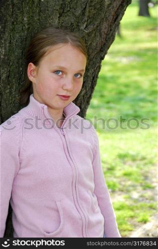 Young girl standing near ancient big tree