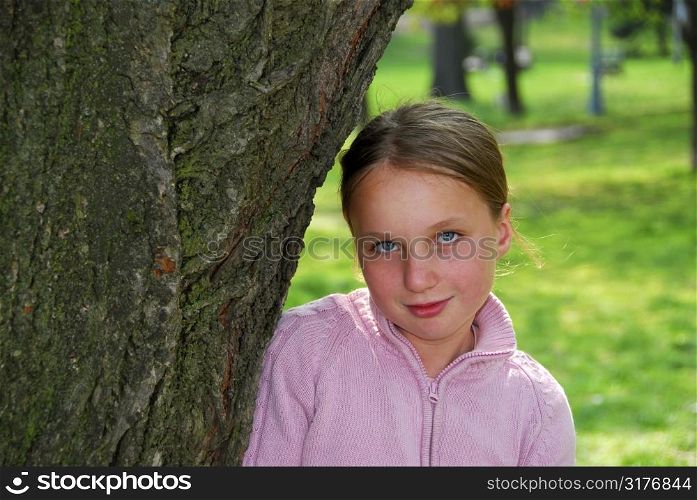 Young girl standing near ancient big tree and smiling, closeup