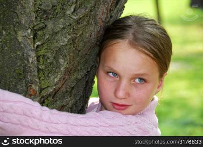 Young girl standing near ancient big tree, closeup