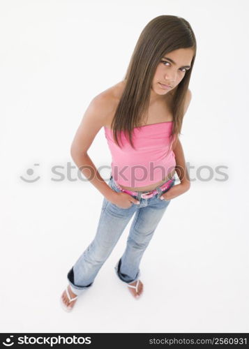 Young girl standing with hands in pockets frowning